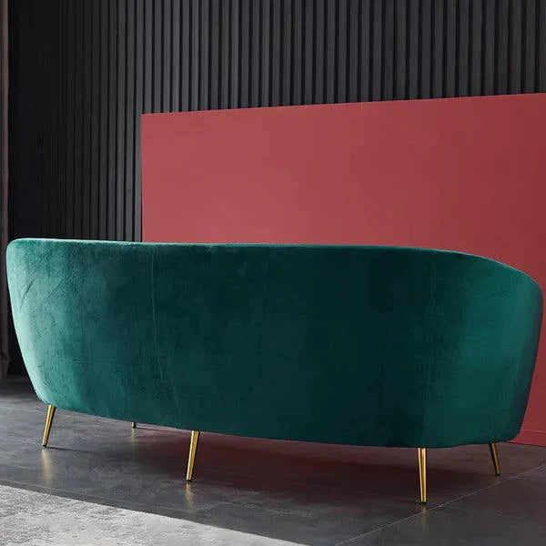 Teal velvet sofa with gold legs against a black and red wall.