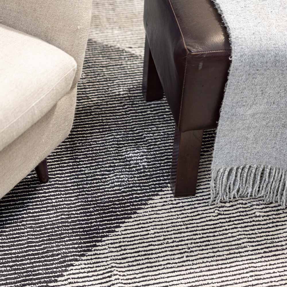 Close-up of a textured black and white rug with furniture corners.