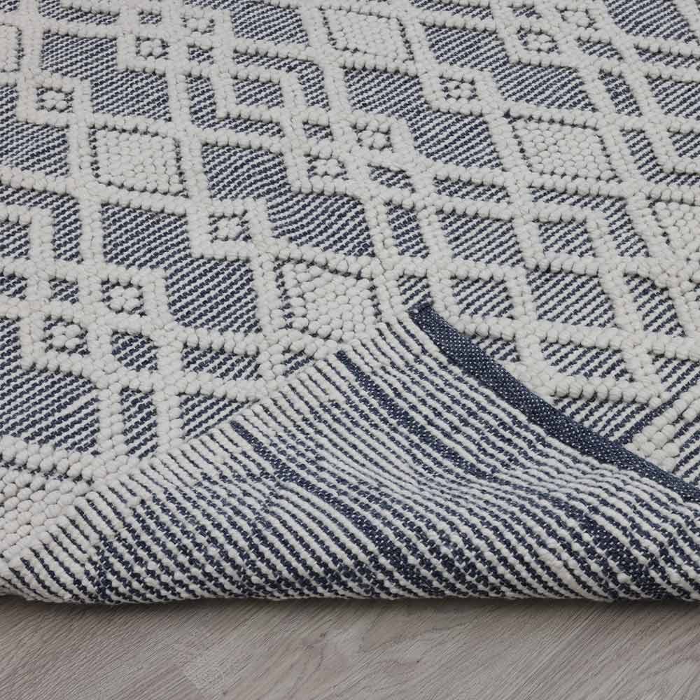 Close-up of a textured blue and white fabric with geometric pattern on a wooden surface.