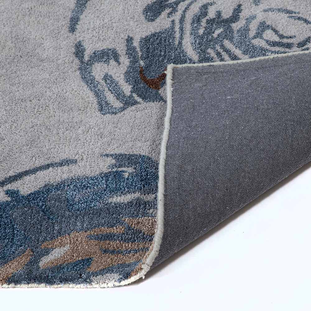 Close-up of a gray and blue patterned rug corner on a white background