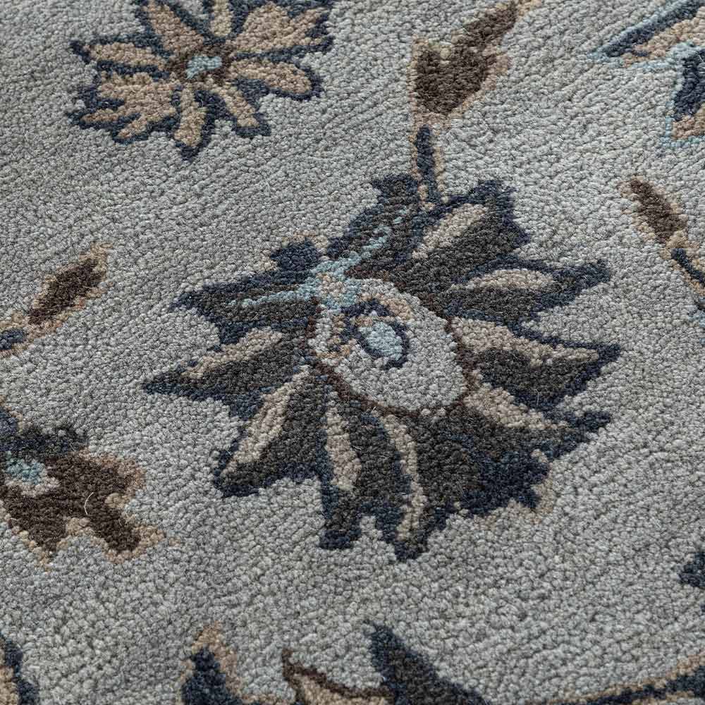 Close-up of a patterned rug with geometric designs in brown and beige on a gray background