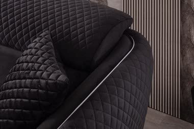 Black quilted blanket draped over a chair with a neutral background