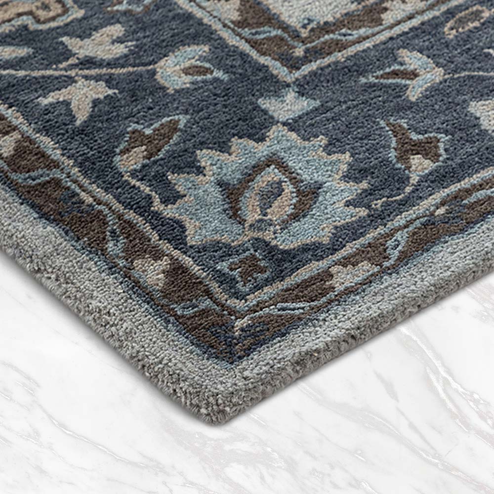 Close-up of a blue and gray patterned rug on a white floor.