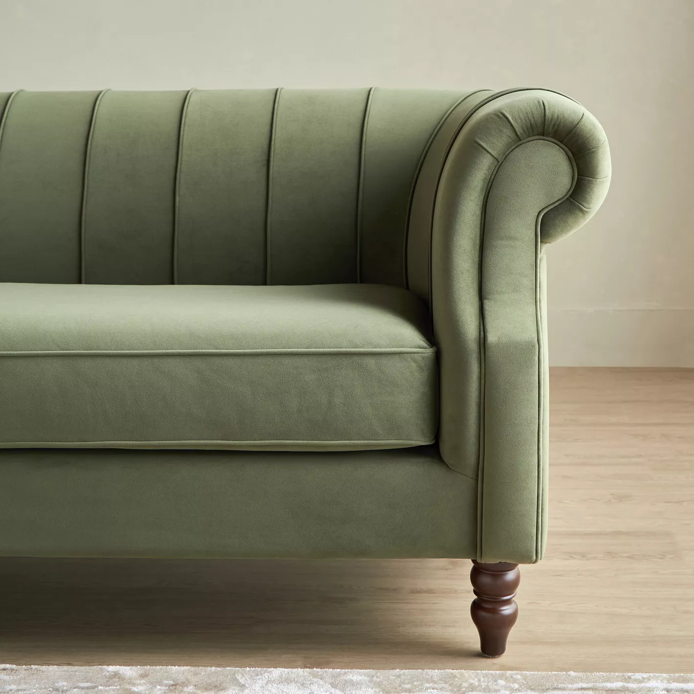 Green velvet sofa with wooden legs on a neutral background