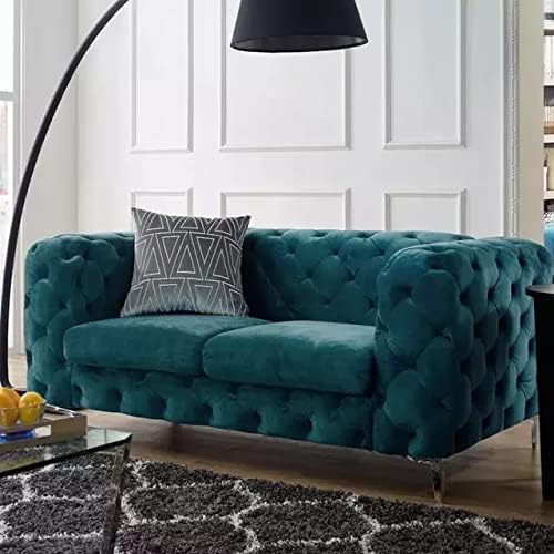 Teal tufted sofa with a decorative pillow in a living room setting.