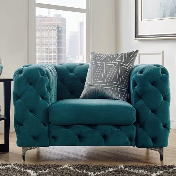 Teal armchair with a patterned pillow in a room with large windows.