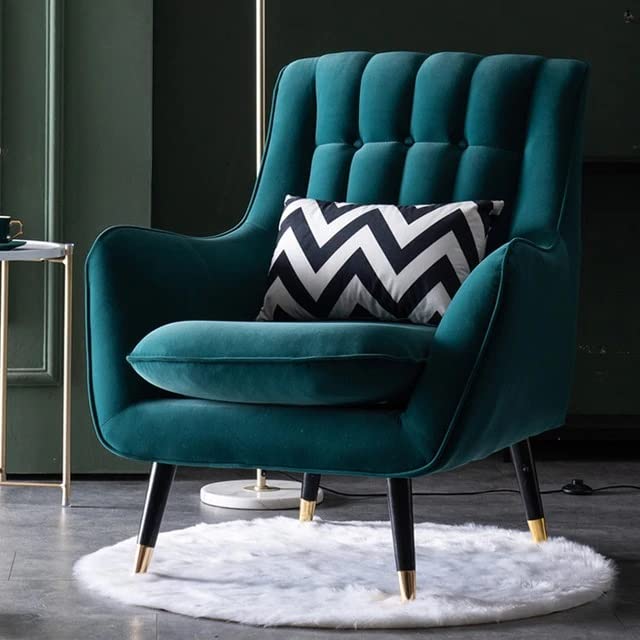 Teal armchair with a black and white zigzag pillow on a dark floor.