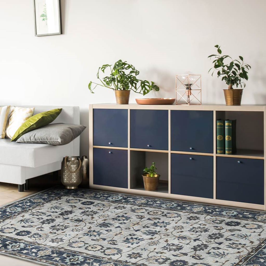 Modern living room with a blue storage unit, floral rug, and decorative plants.