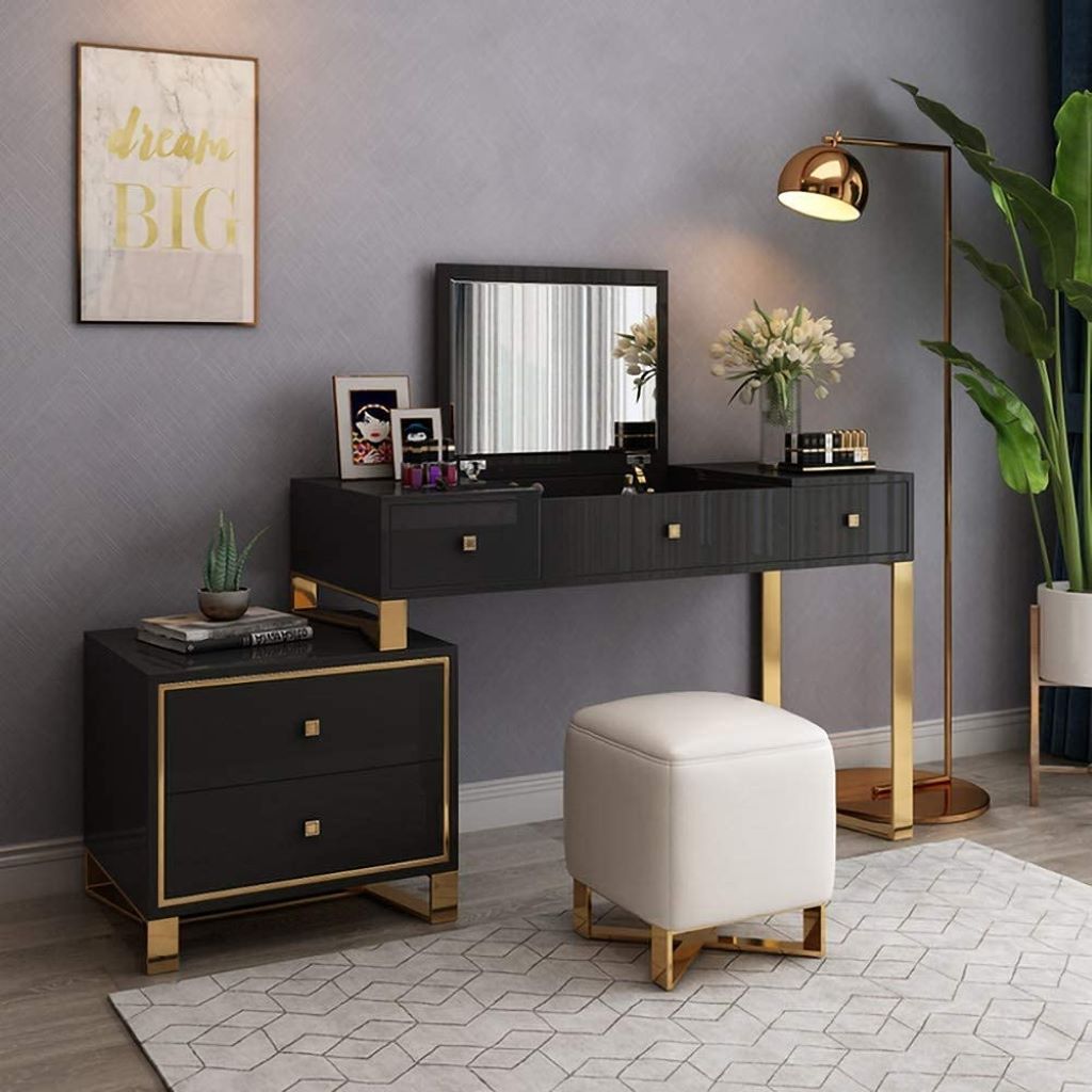 Modern bedroom setup with black vanity table, white ottoman, and decorative elements.