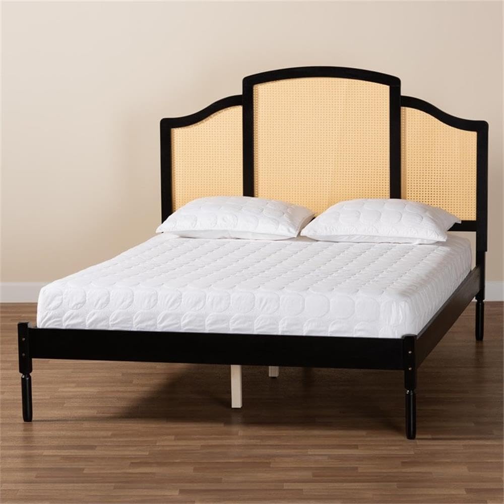 Bed with black frame and beige headboard on a wooden floor.