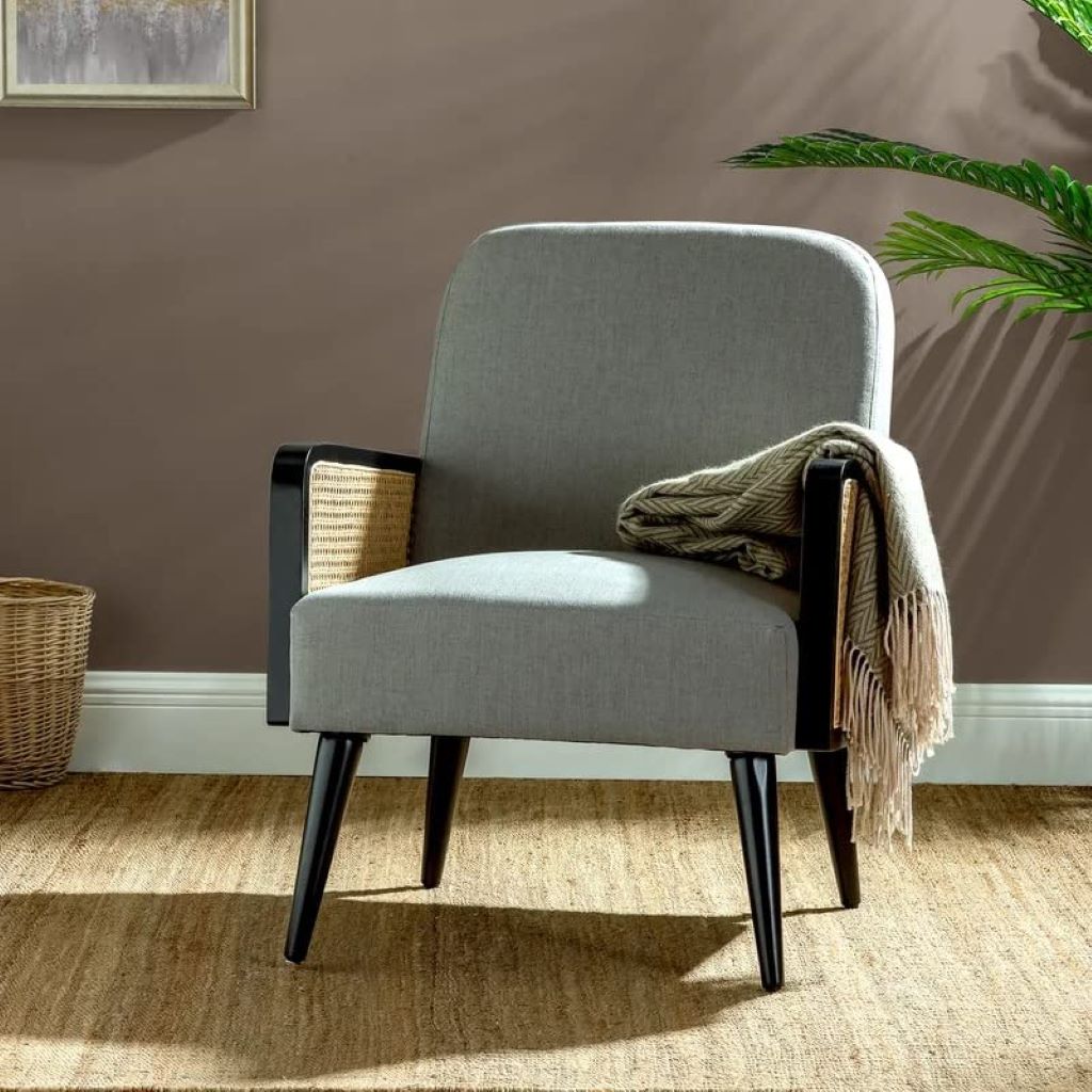 Gray armchair with black legs in a room with a brown wall and a plant.