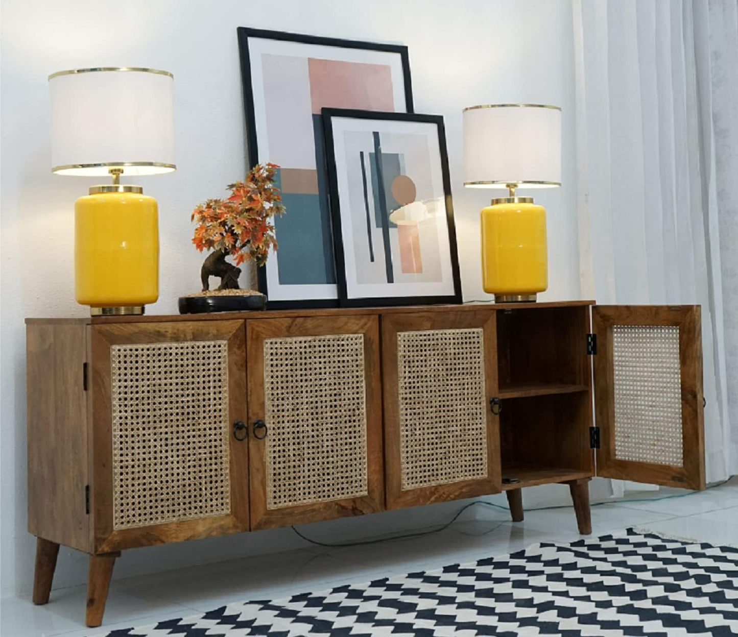 Wooden sideboard with yellow lamps and framed art in a room.