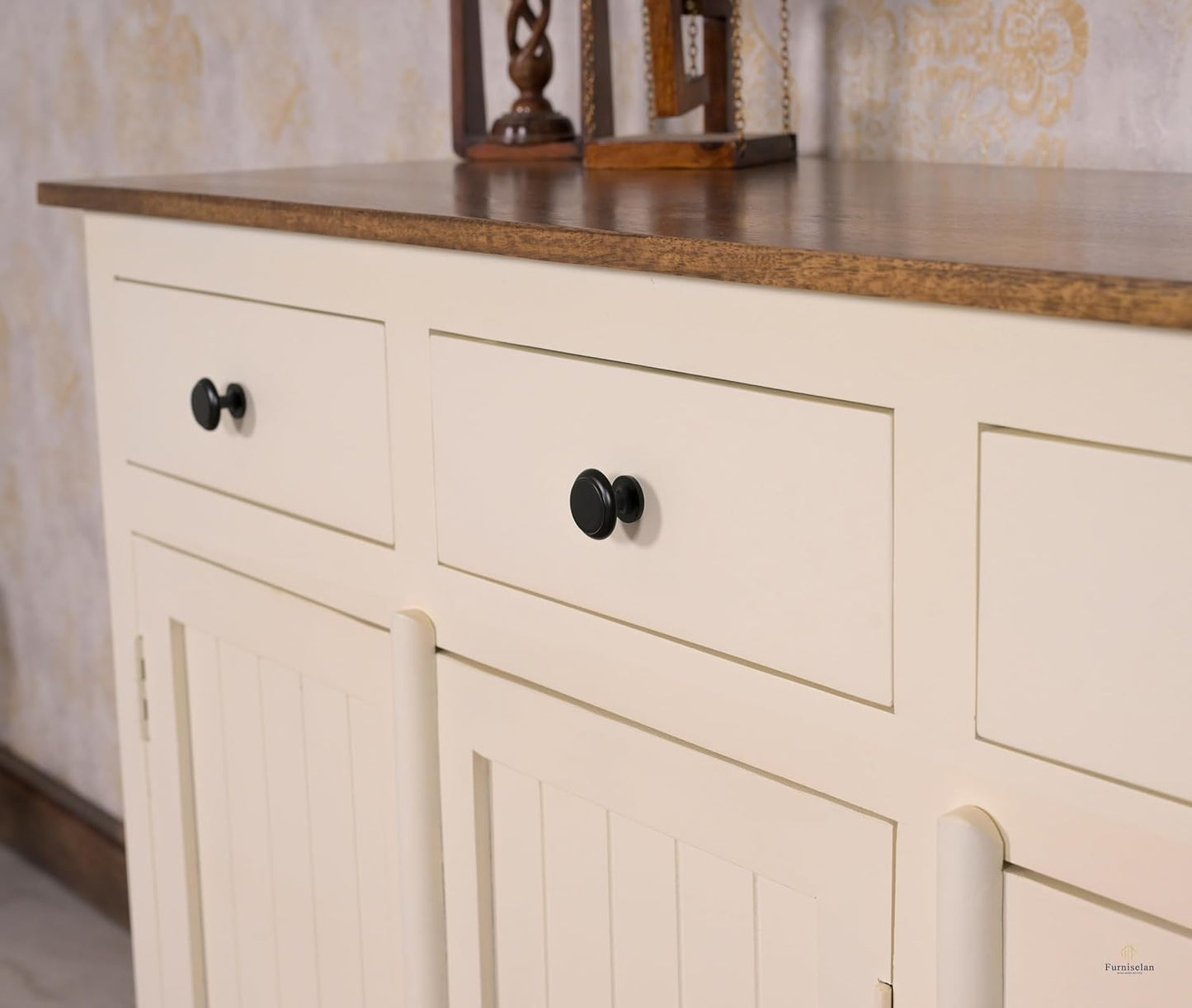Beige cabinet with black knobs against a patterned wall.