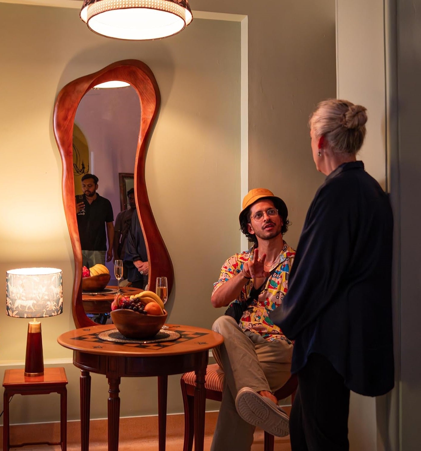 Two people sitting at a table with a unique shaped mirror behind them