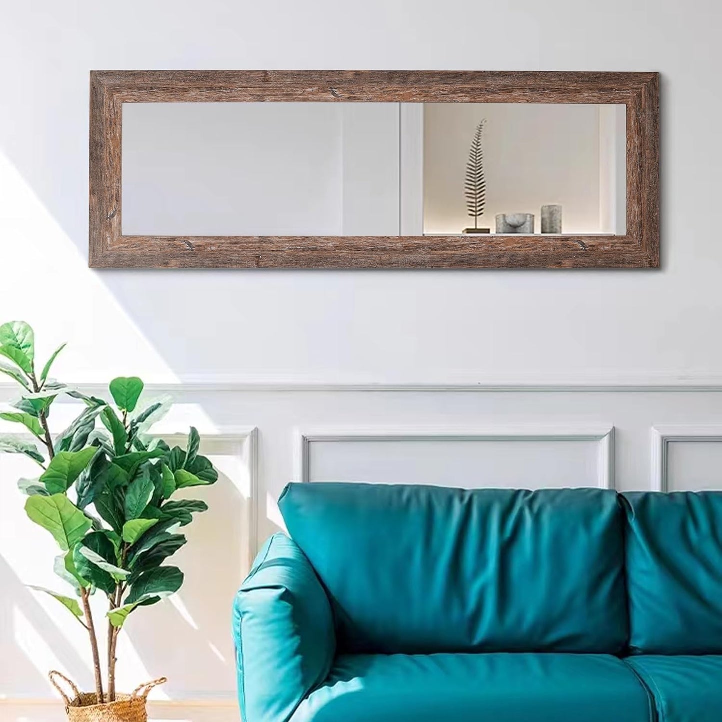 Teal sofa with a large wooden-framed mirror on the wall above it.