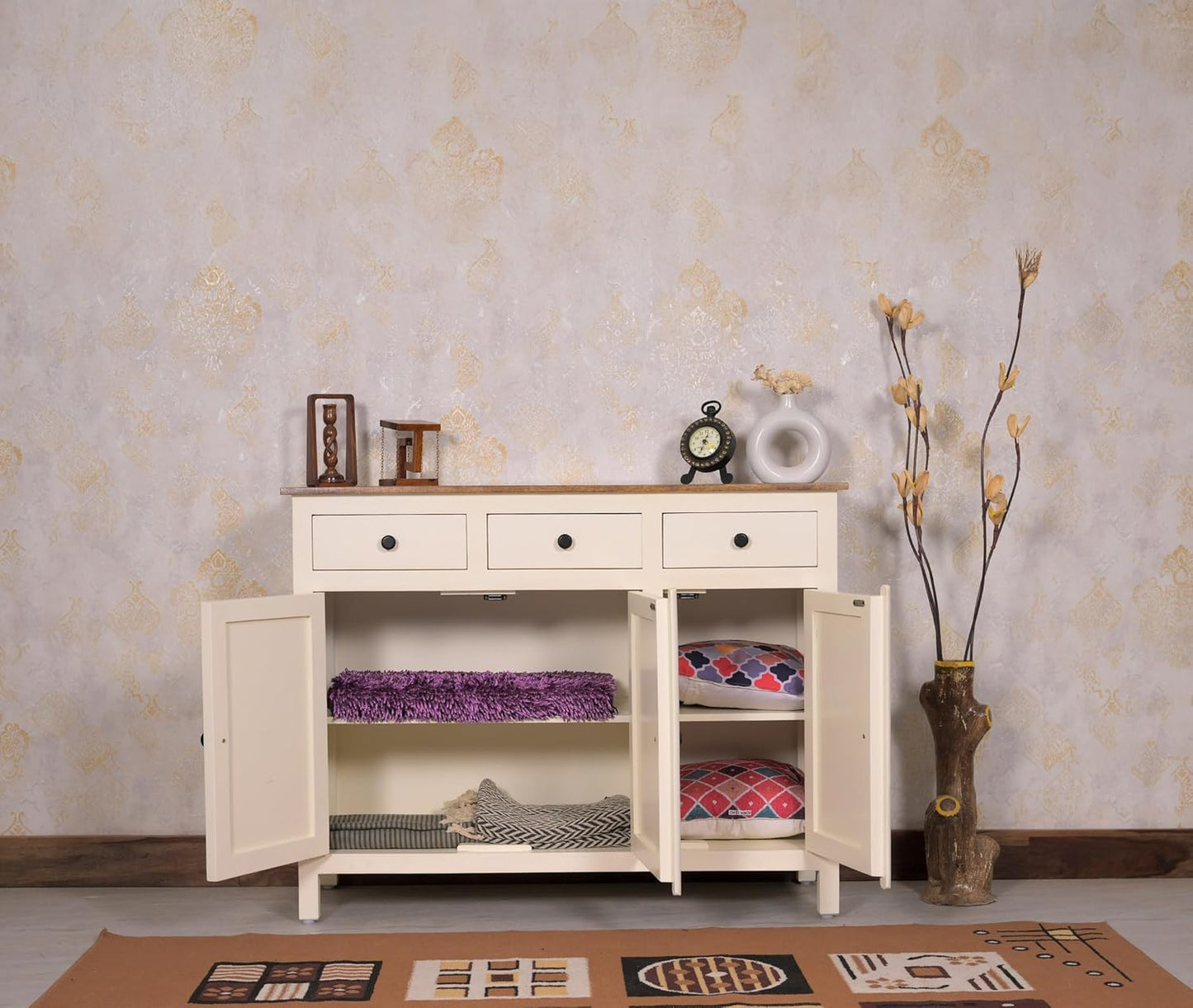 White wooden sideboard with open doors displaying various items against a patterned wall.