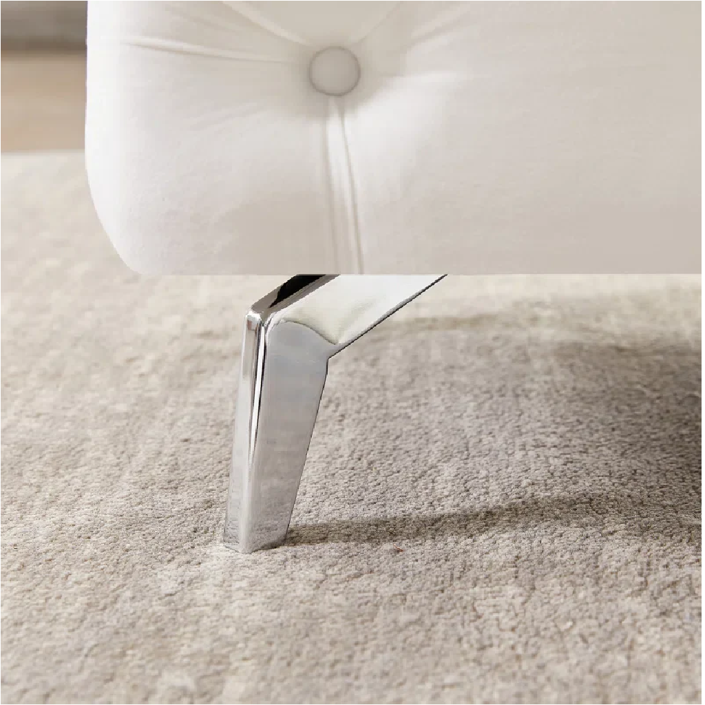 Close-up of a white upholstered chair with a chrome leg on a beige carpet.