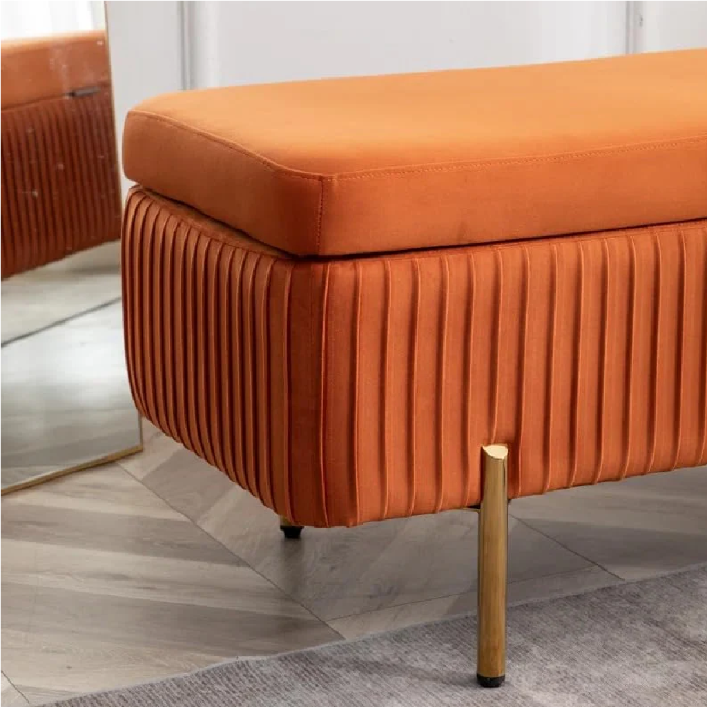 Orange upholstered bench with pleated design on a wooden floor.