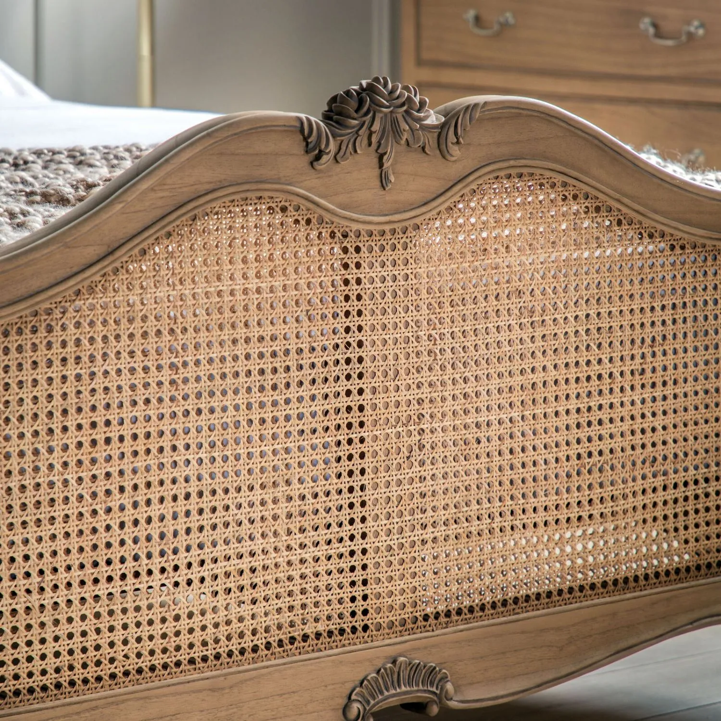 Close-up of a wooden headboard with wicker design and decorative carvings.