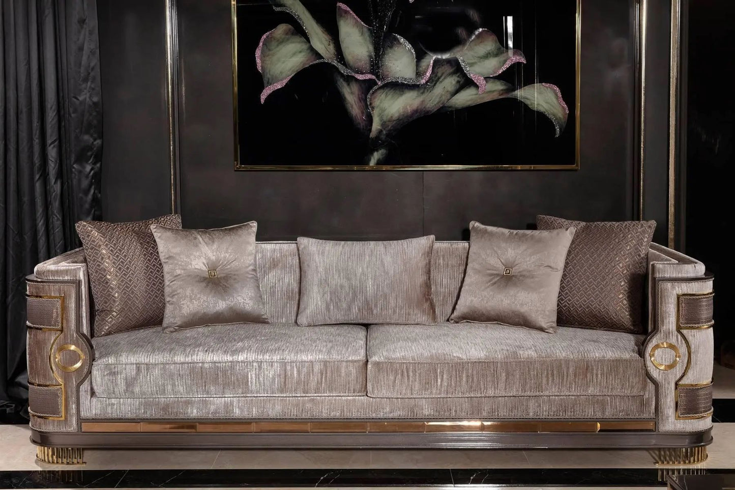 Luxury sofa with decorative pillows against a dark wall with a framed plant art piece.