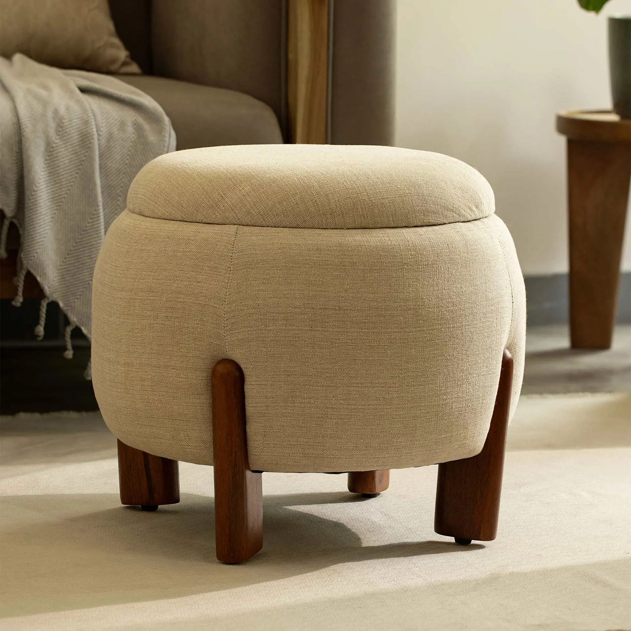 Beige ottoman with wooden legs in a living room setting