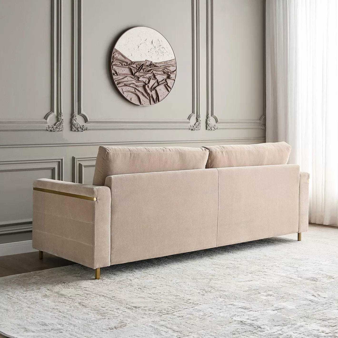 Beige sofa in a room with decorative wall molding and a circular artwork.