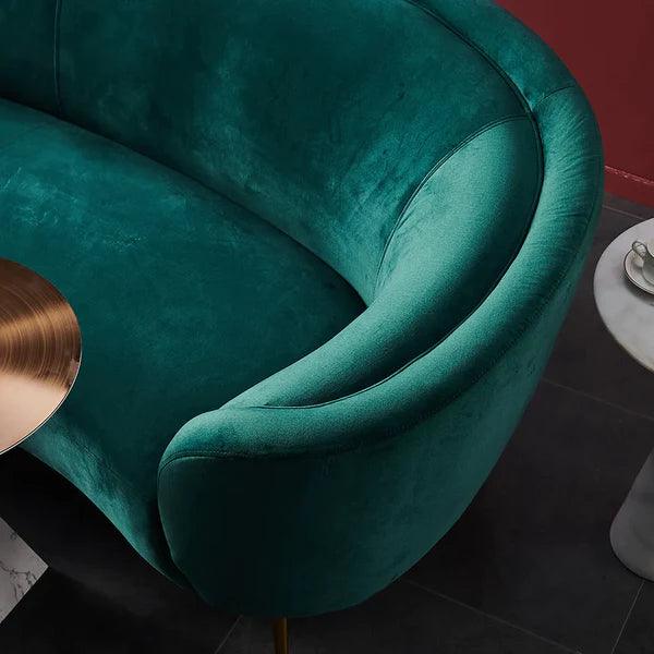 Teal velvet armchair with a gold side table in a room setting.