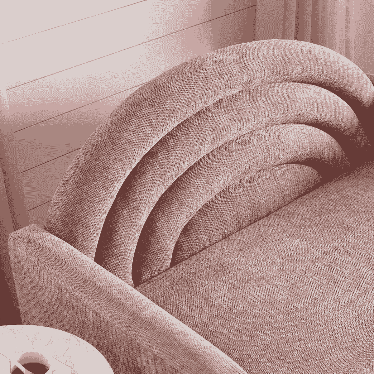 Close-up of a pink upholstered chair with a wooden wall in the background