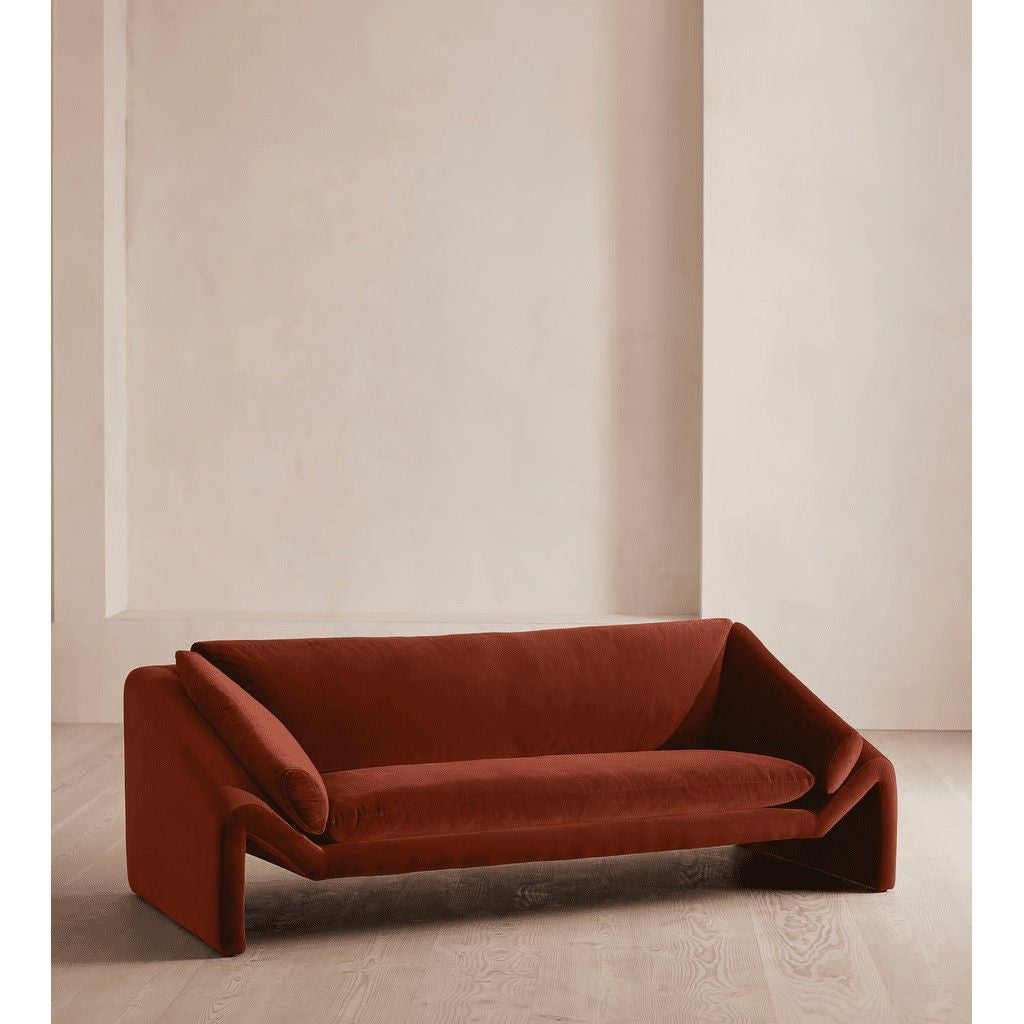 Brown sofa in a minimalistic room with beige walls and floor.