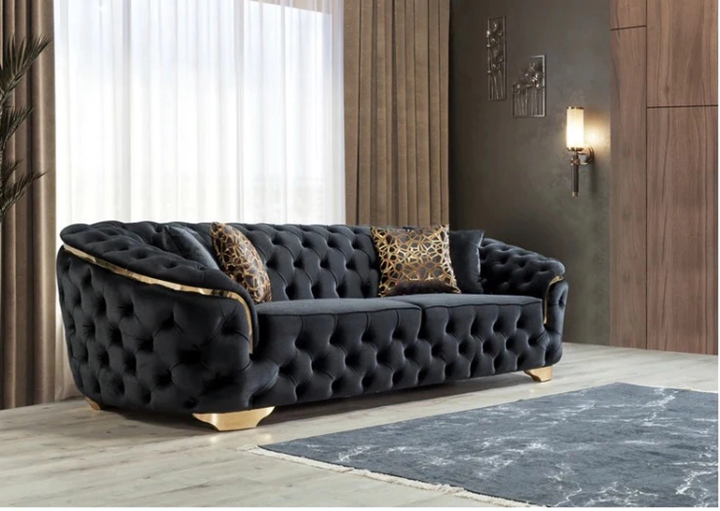 Black tufted sofa with leopard print pillows in a room with wooden floor and wall.