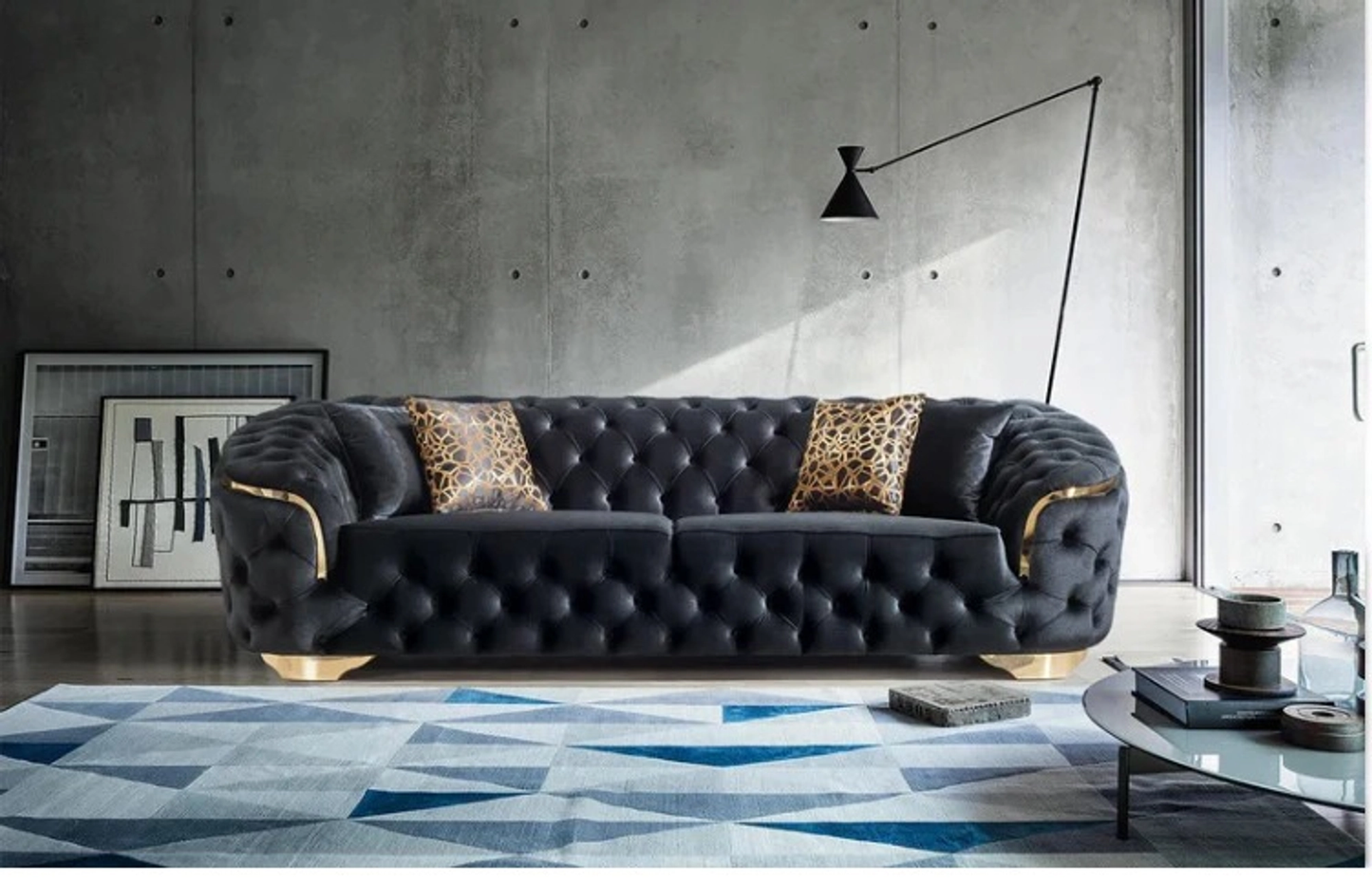 Modern living room with a black tufted sofa, geometric rug, and abstract art.
