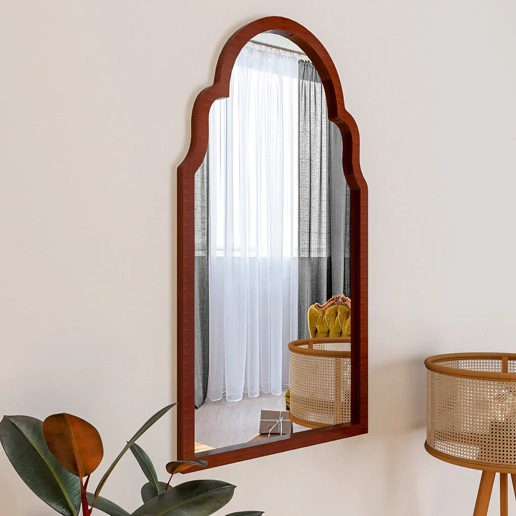 Wooden-framed mirror on a wall with a plant and basket in the foreground