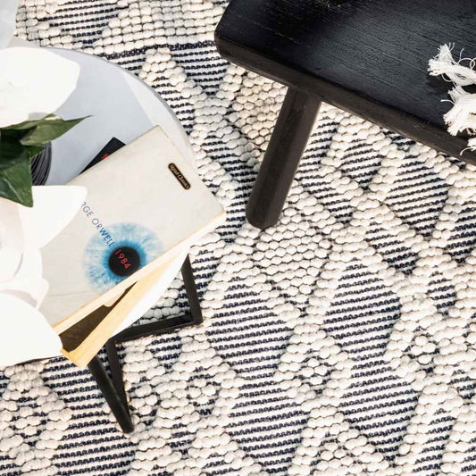 Phone, books, and a plant on a textured black and white rug