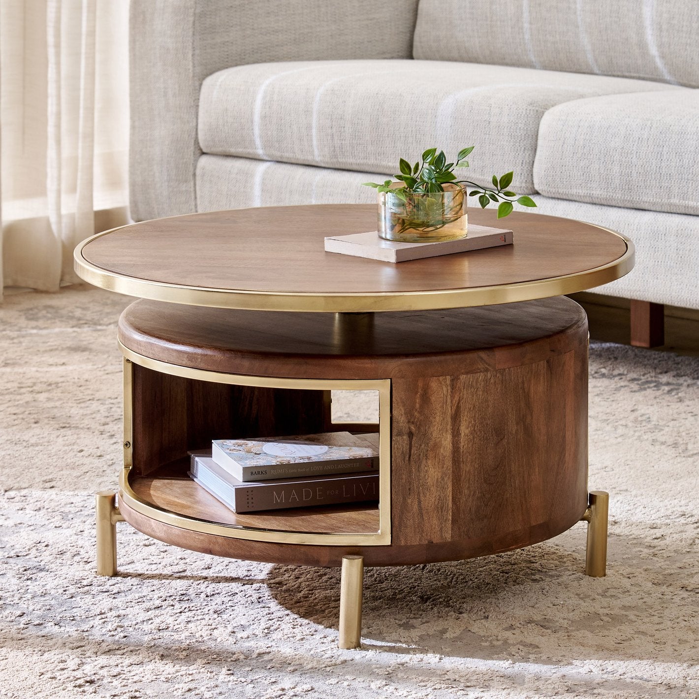 Round wooden coffee table with gold accents in a living room setting