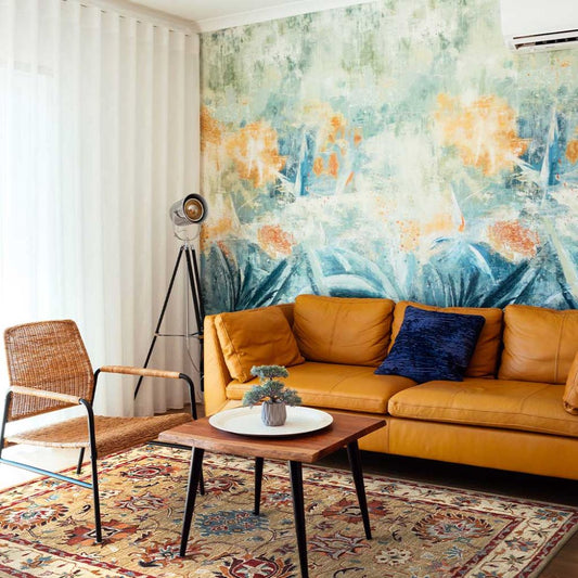 Living room with a mustard yellow sofa, wicker chair, and abstract wall art.