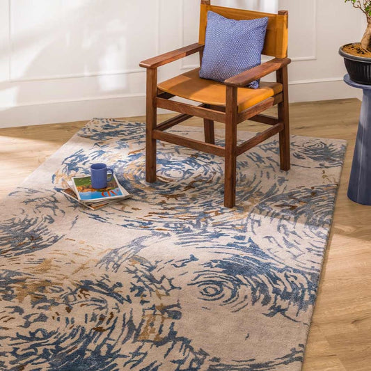 Wooden chair with a blue cushion on a patterned rug in a room.