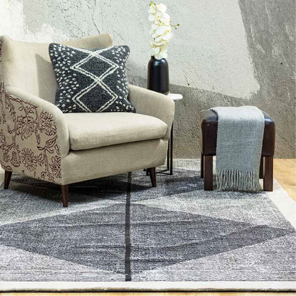 Beige armchair with decorative pillow and gray rug in a room with textured walls.