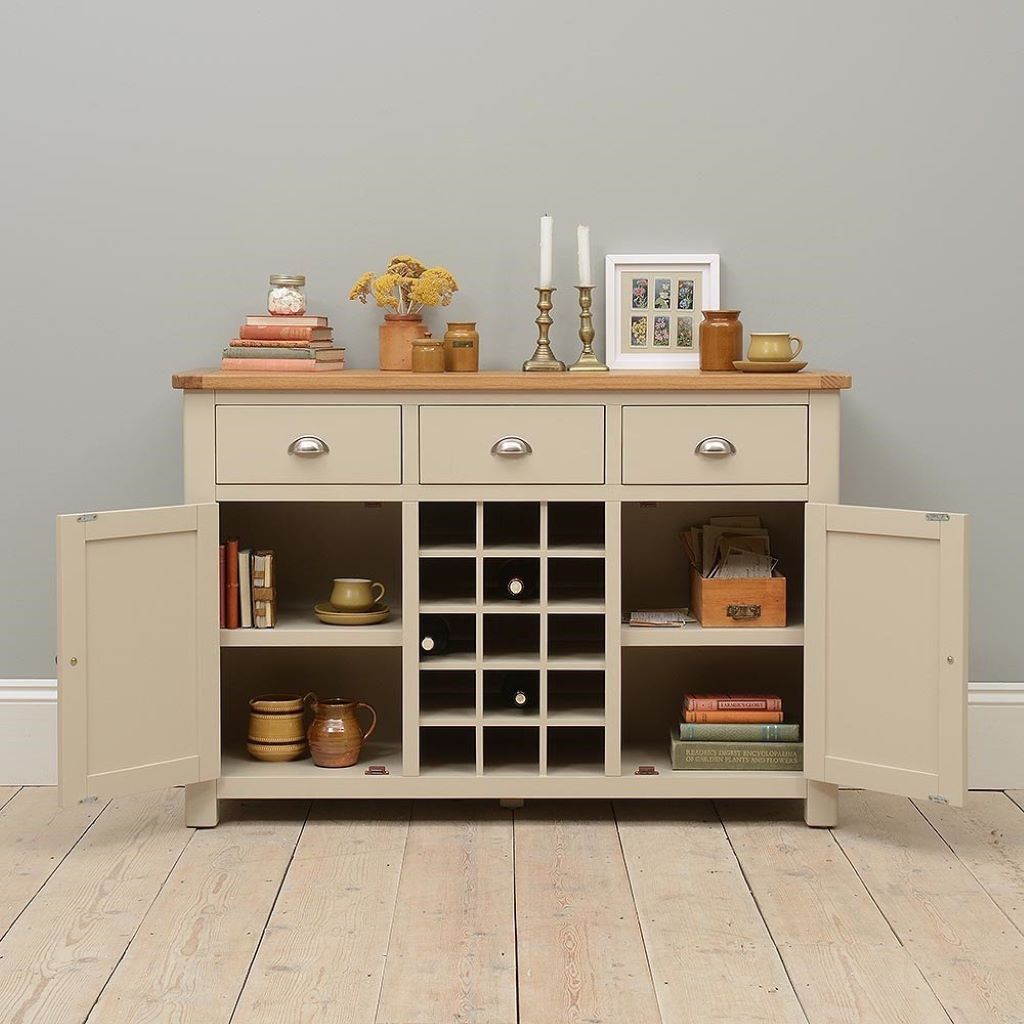 Wooden sideboard with open doors displaying various items against a gray wall.