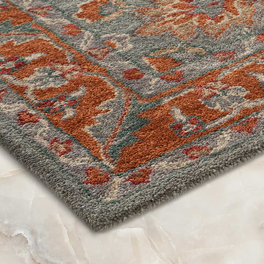 Close-up of a patterned rug with orange and gray colors on a marble floor.