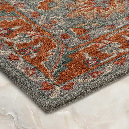 Close-up of a patterned rug with orange and gray colors on a marble floor.