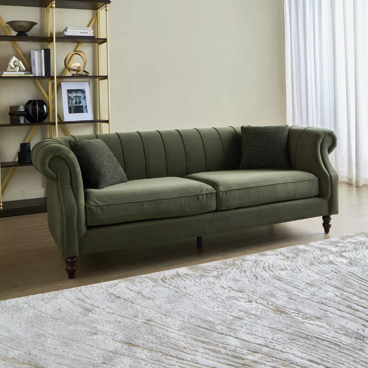 Green sofa in a living room with a decorative shelf and light-colored walls.