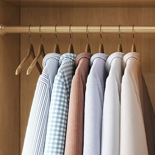 Row of shirts on wooden hangers against a wooden wardrobe background