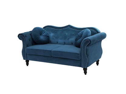 Blue velvet sofa with tufted backrest and nailhead trim on a white background