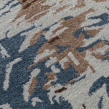 Close-up of a textured rug with abstract pattern in blue, brown, and gray.