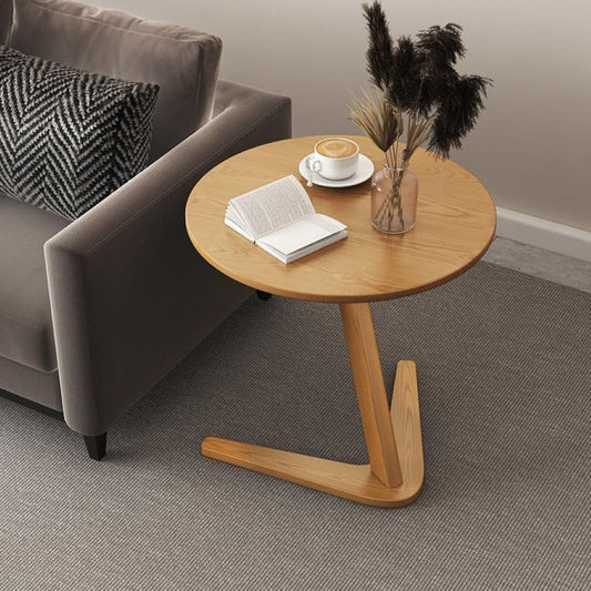Wooden side table with a cup of coffee, book, and vase in a living room setting.