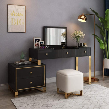 Modern bedroom setup with black vanity table, white ottoman, and decorative elements.