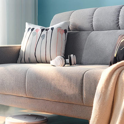 Gray sofa with decorative pillows and a robot vacuum cleaner on a light blue wall background