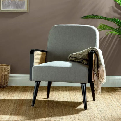 Gray armchair with black legs in a room with a brown wall and a plant.