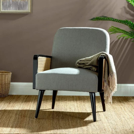 Gray armchair with black legs in a room with a brown wall and a plant.