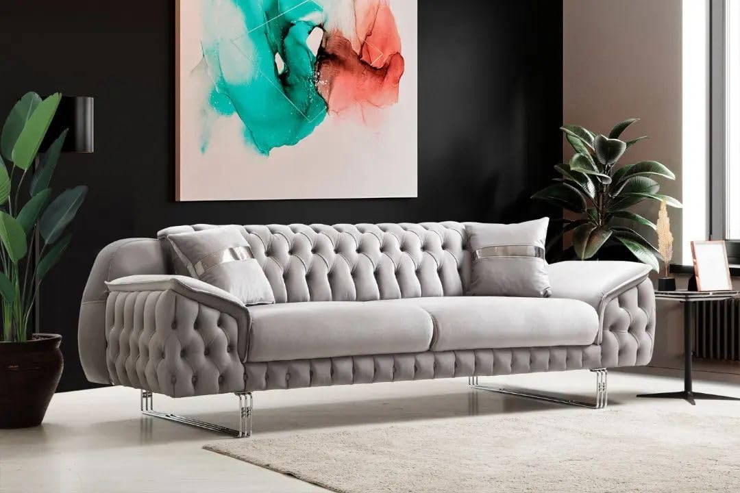 Gray tufted sofa in a modern living room with abstract art and plants.